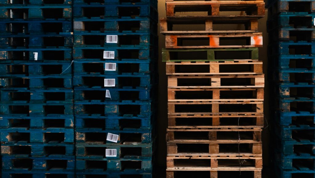 Close-up of stacked wooden pallets with barcodes in a warehouse environment.